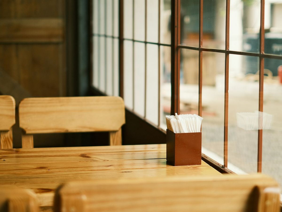 Simple timber booth seating and table beside a large window.